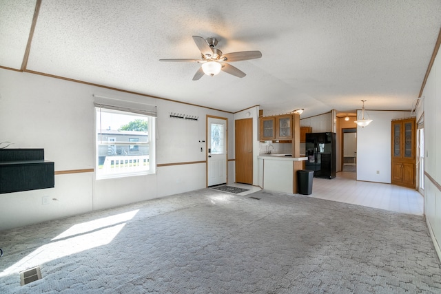 unfurnished living room with light colored carpet, lofted ceiling, ceiling fan, and a textured ceiling