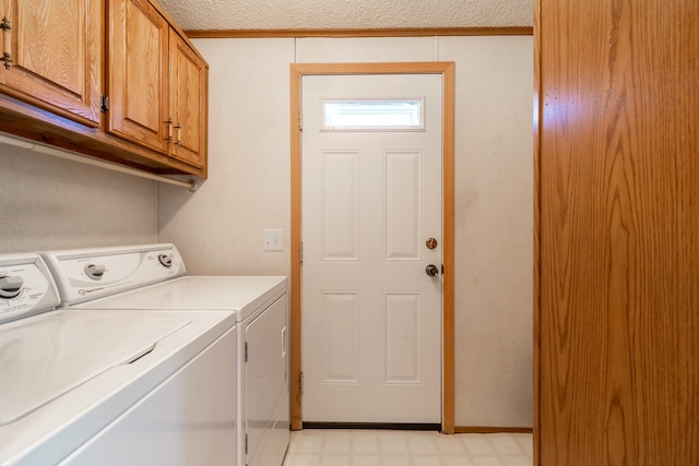 clothes washing area with a textured ceiling, washing machine and dryer, and cabinets