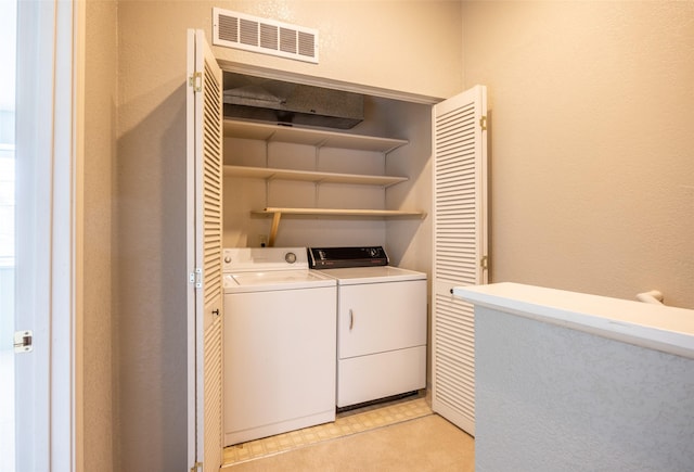 clothes washing area with a textured wall, laundry area, washing machine and dryer, and visible vents