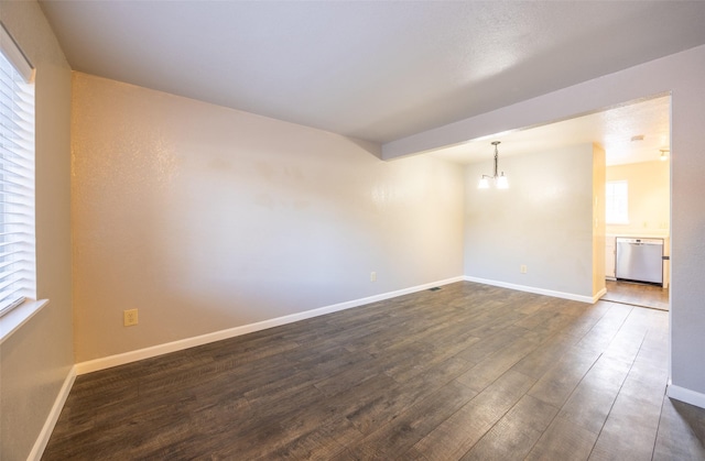 unfurnished room featuring a notable chandelier, dark wood-style flooring, and baseboards