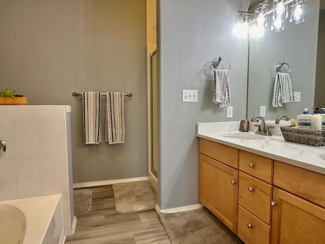 bathroom with wood-type flooring, vanity, and independent shower and bath