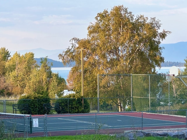 view of tennis court with a water and mountain view