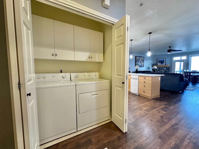 clothes washing area with ceiling fan, dark hardwood / wood-style floors, cabinets, washing machine and dryer, and a textured ceiling