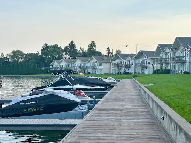 view of dock featuring a lawn and a water view