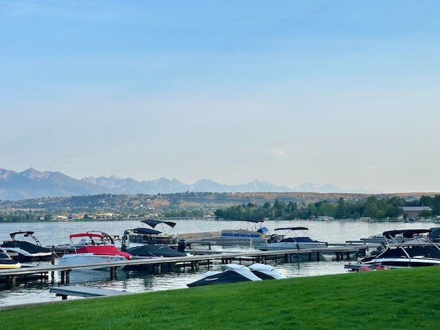 dock area featuring a water and mountain view and a lawn