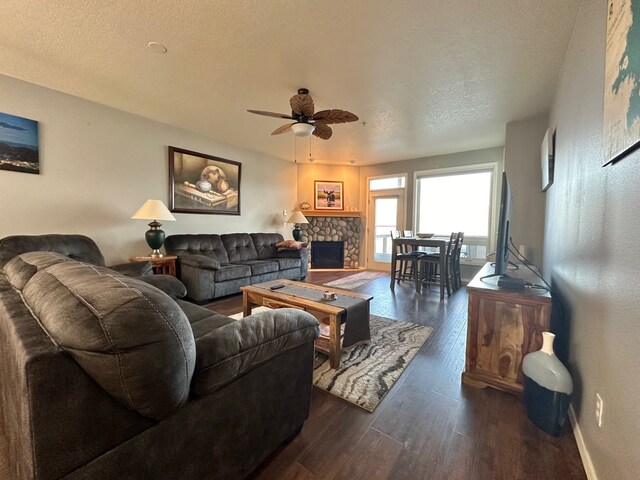 100 Rocky Point Rd Unit B-2, Polson, MT 59860 - living room with a ceiling fan, a textured ceiling, a fireplace, baseboards, and dark wood-type flooring