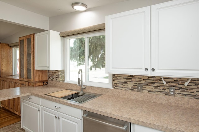 kitchen featuring stainless steel dishwasher, a sink, decorative backsplash, and white cabinets