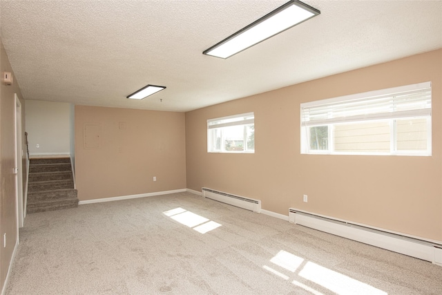 spare room featuring stairway, carpet, a baseboard heating unit, and a textured ceiling