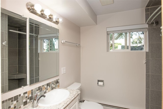 bathroom with vanity, tiled shower, toilet, and tasteful backsplash