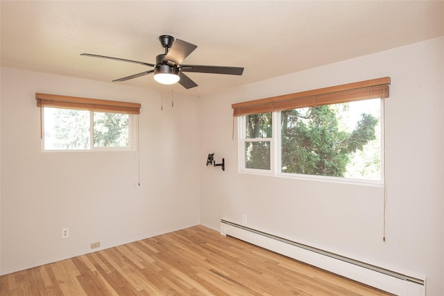 empty room featuring baseboards, a ceiling fan, light wood finished floors, and a baseboard heating unit