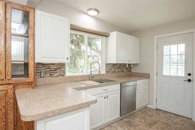 kitchen featuring a sink, dishwasher, light countertops, white cabinetry, and tasteful backsplash