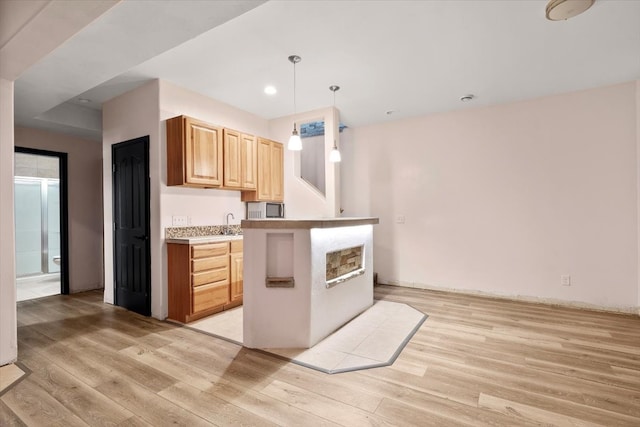 kitchen featuring pendant lighting, light hardwood / wood-style flooring, sink, and light brown cabinets