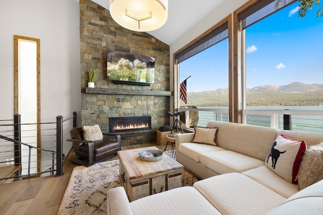 living room with lofted ceiling, a water and mountain view, hardwood / wood-style flooring, and a fireplace