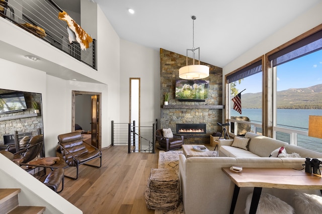 living room with plenty of natural light, a water and mountain view, a fireplace, and light hardwood / wood-style flooring