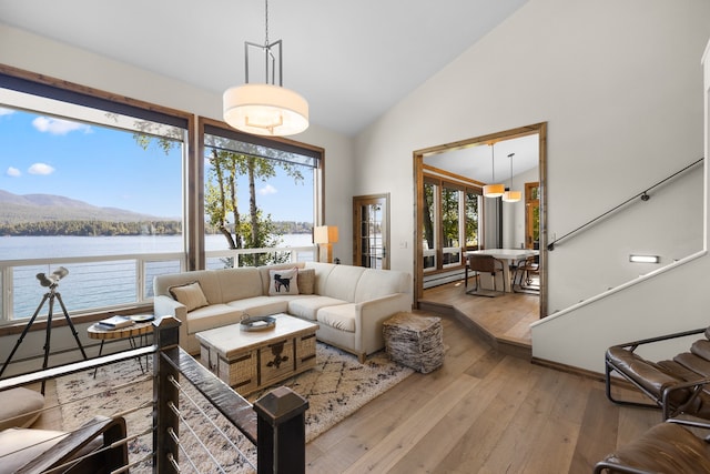 living room with a water and mountain view, light hardwood / wood-style flooring, and high vaulted ceiling