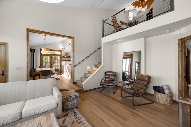 living room with french doors, high vaulted ceiling, and hardwood / wood-style floors