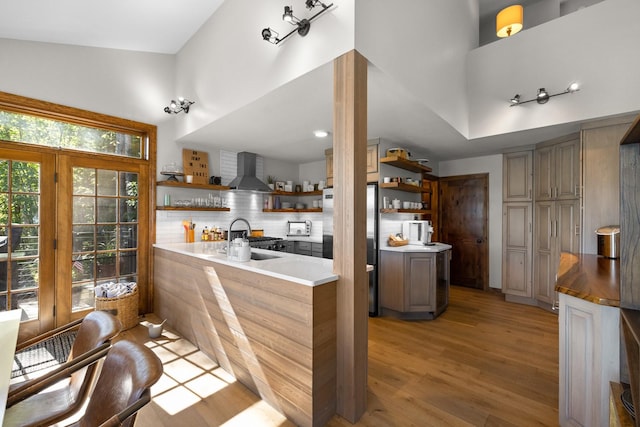 1320 W Lakeshore Dr, Whitefish, MT 59937 - kitchen with open shelves, wall chimney range hood, fridge, light wood-style flooring, and decorative backsplash