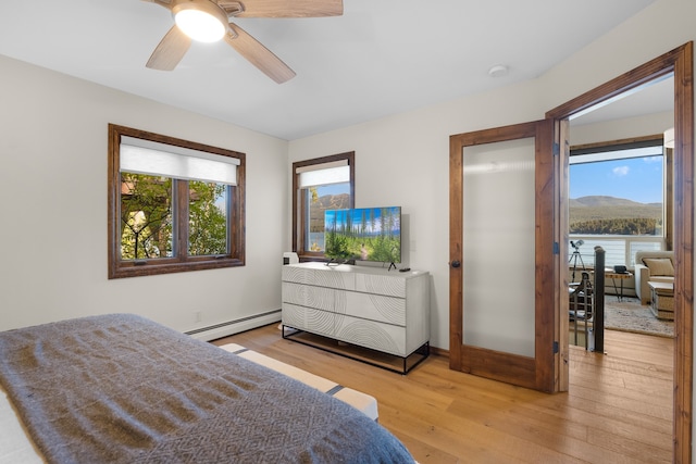 bedroom featuring a baseboard heating unit, ceiling fan, and light hardwood / wood-style flooring