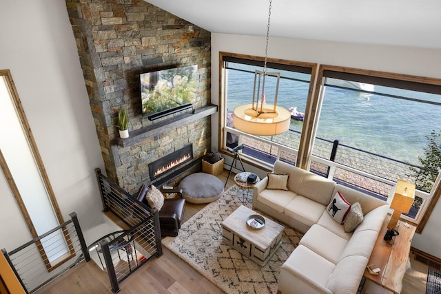1320 W Lakeshore Dr, Whitefish, MT 59937 - living area with wood finished floors, a stone fireplace, lofted ceiling, and a water view