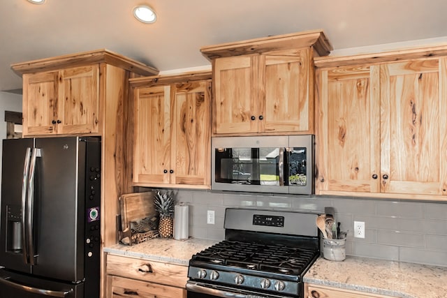 kitchen featuring appliances with stainless steel finishes, tasteful backsplash, light stone counters, and light brown cabinets