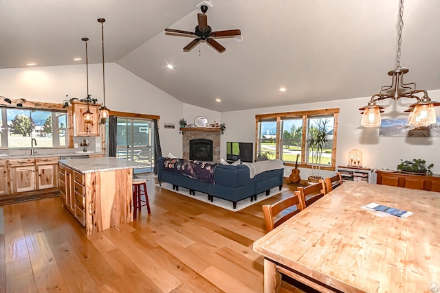 dining area with ceiling fan with notable chandelier, high vaulted ceiling, and light hardwood / wood-style floors