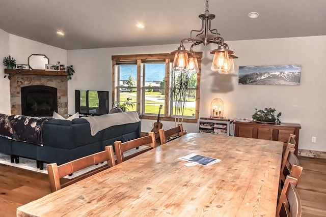 dining room featuring a notable chandelier, hardwood / wood-style floors, and a fireplace