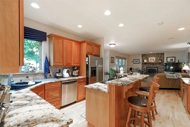 kitchen with a wealth of natural light, a kitchen island, stainless steel appliances, and a sink