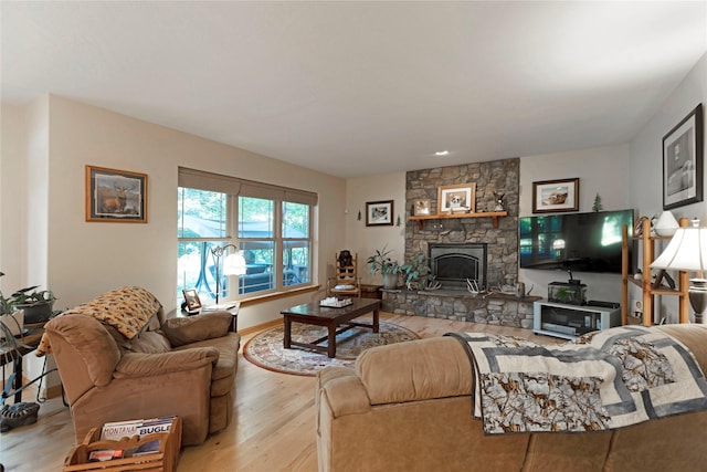 living area featuring light wood-style floors and a stone fireplace