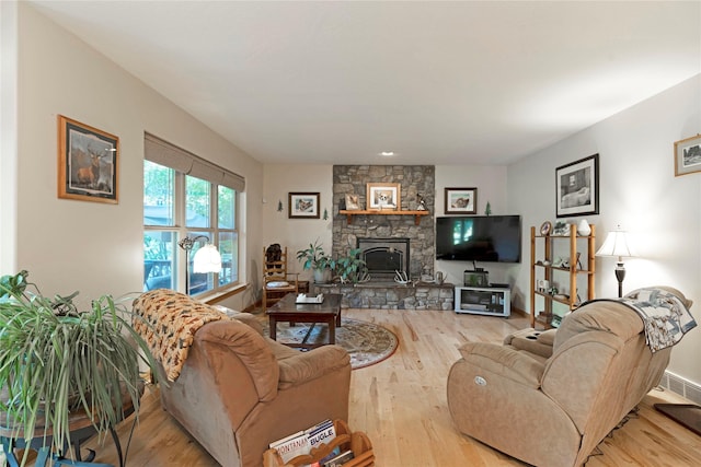 living area with a fireplace, wood finished floors, visible vents, and baseboards