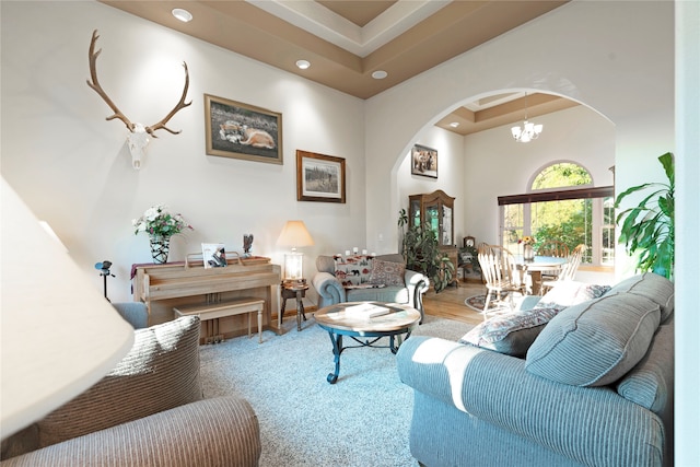 living room featuring a raised ceiling, hardwood / wood-style flooring, and an inviting chandelier