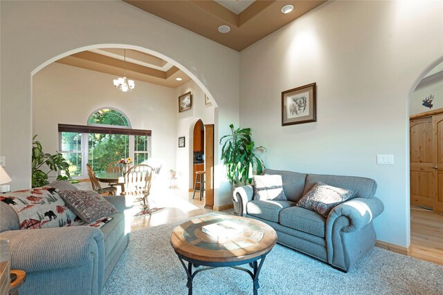 living room featuring a towering ceiling, a notable chandelier, and hardwood / wood-style flooring