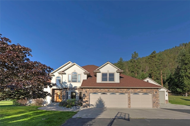 view of front of house featuring a garage, stone siding, driveway, and a front lawn