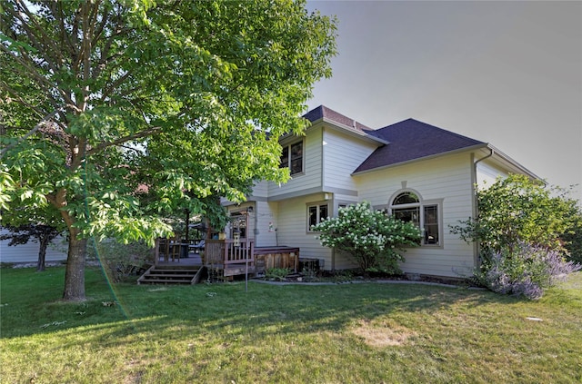 back of property with a shingled roof, a lawn, and a wooden deck