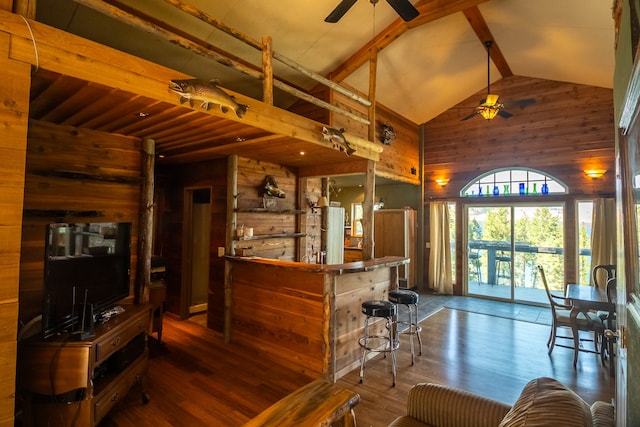 interior space featuring dark wood-type flooring, wood walls, ceiling fan, and beamed ceiling