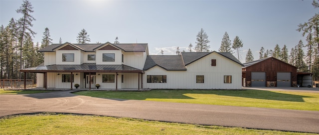 modern farmhouse with a porch, a garage, an outbuilding, and a front lawn