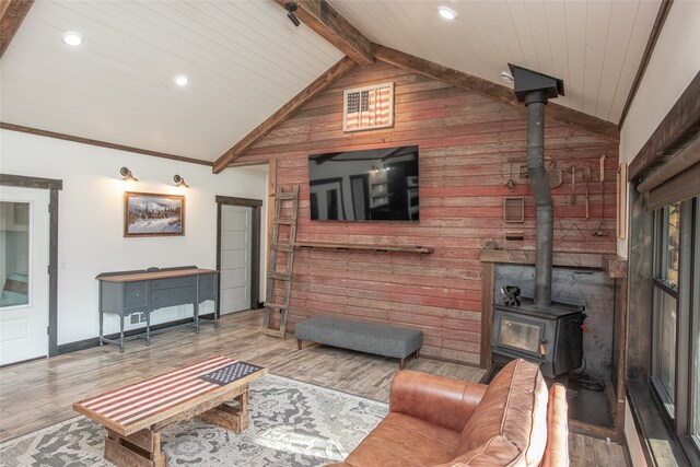 living room featuring wooden walls, wood-type flooring, lofted ceiling with beams, wooden ceiling, and a wood stove