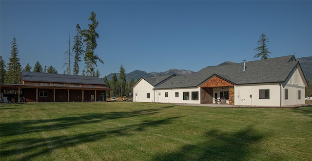 back of house with a lawn, a mountain view, and solar panels