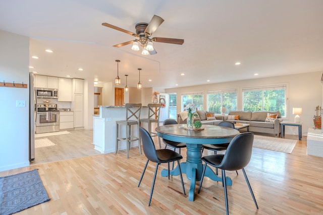 dining space with ceiling fan and light wood-type flooring