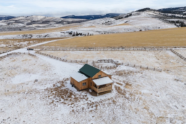 snowy aerial view featuring a mountain view and a rural view