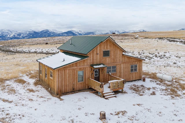 snow covered rear of property featuring a mountain view