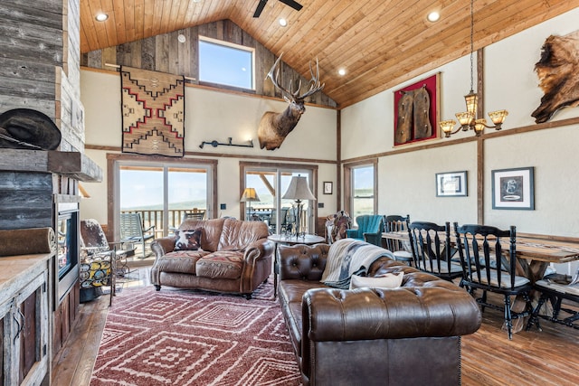 living room with a large fireplace, wooden ceiling, a healthy amount of sunlight, and high vaulted ceiling