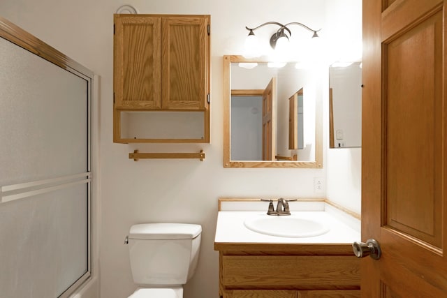 bathroom featuring vanity, toilet, and an enclosed shower