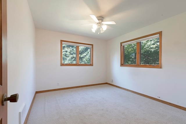 carpeted spare room with ceiling fan and plenty of natural light