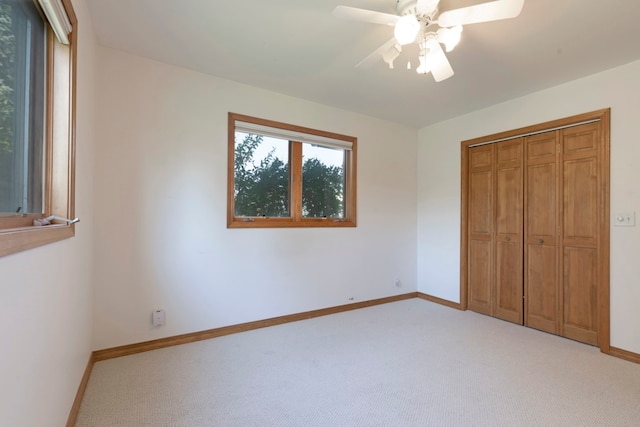 unfurnished bedroom featuring ceiling fan, light colored carpet, and a closet