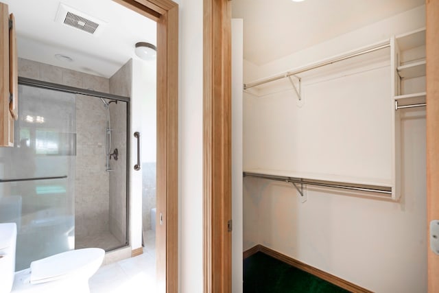 bathroom featuring tile patterned flooring, toilet, and an enclosed shower