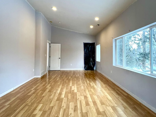 empty room with high vaulted ceiling and light hardwood / wood-style flooring