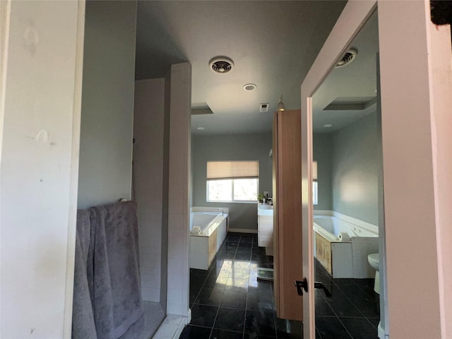 bathroom with a relaxing tiled tub, toilet, and tile patterned floors