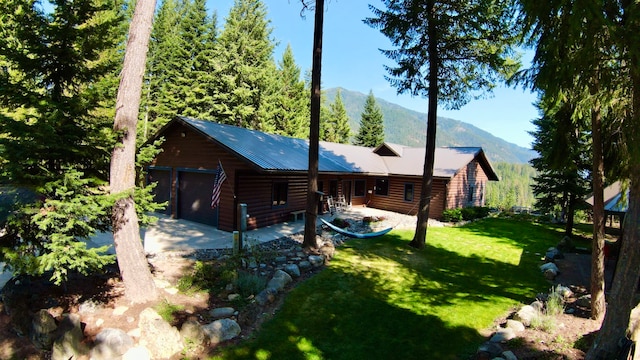 rear view of house with a mountain view, a garage, and a lawn