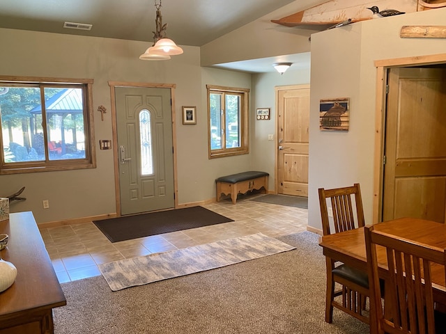 tiled foyer entrance with vaulted ceiling, baseboards, visible vents, and a wealth of natural light