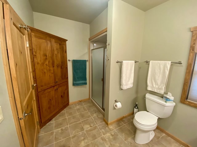 bathroom featuring baseboards, toilet, and a stall shower